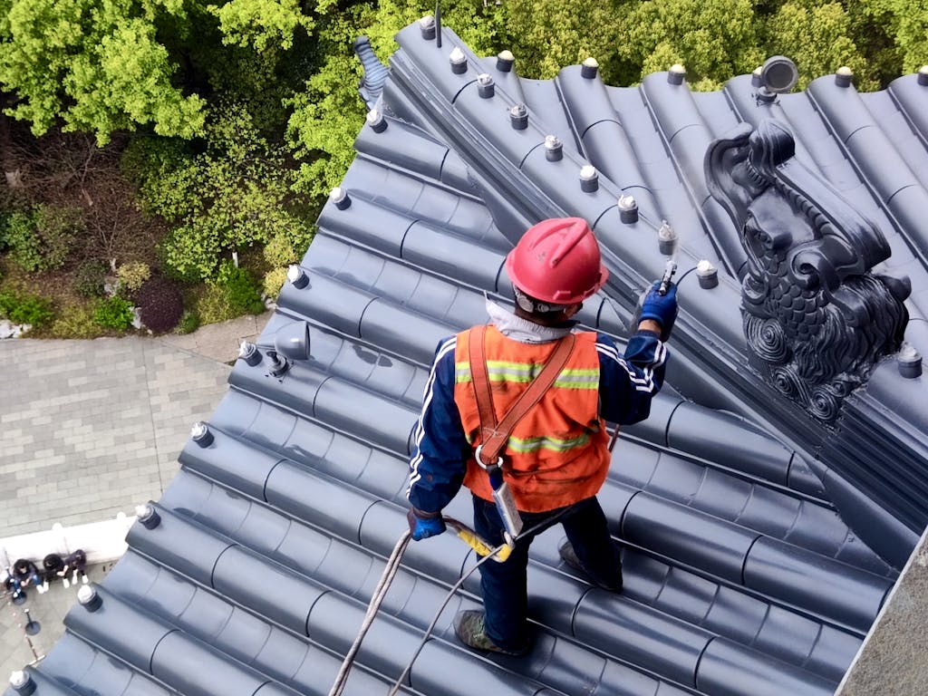 Roof worker in Hangzhou, China, uses safety gear while maintaining traditional temple roof.